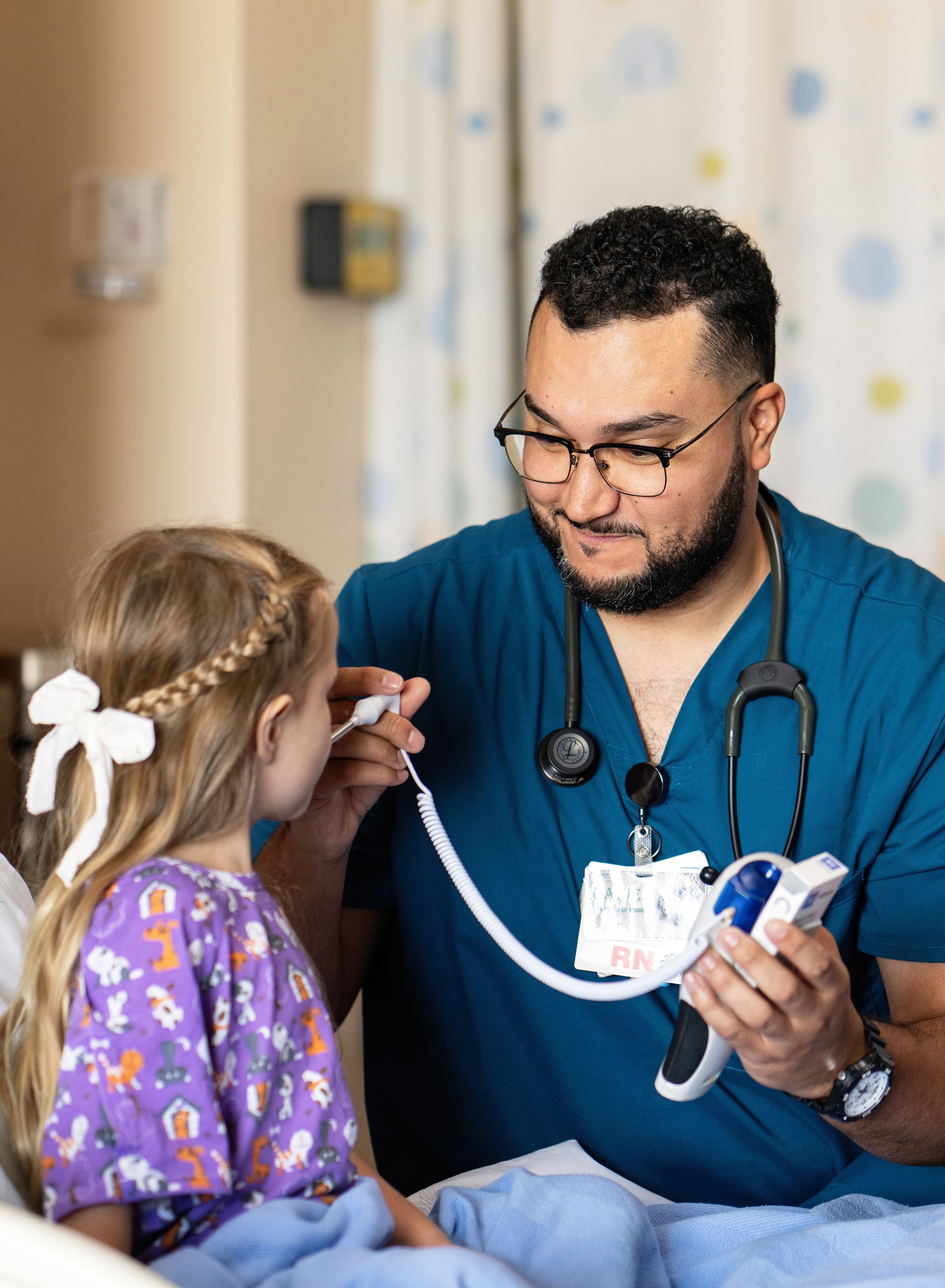 Image of child smiling at camera and pointing in classroom setting.