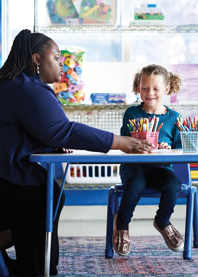 Image of therapist and child coloring at table.